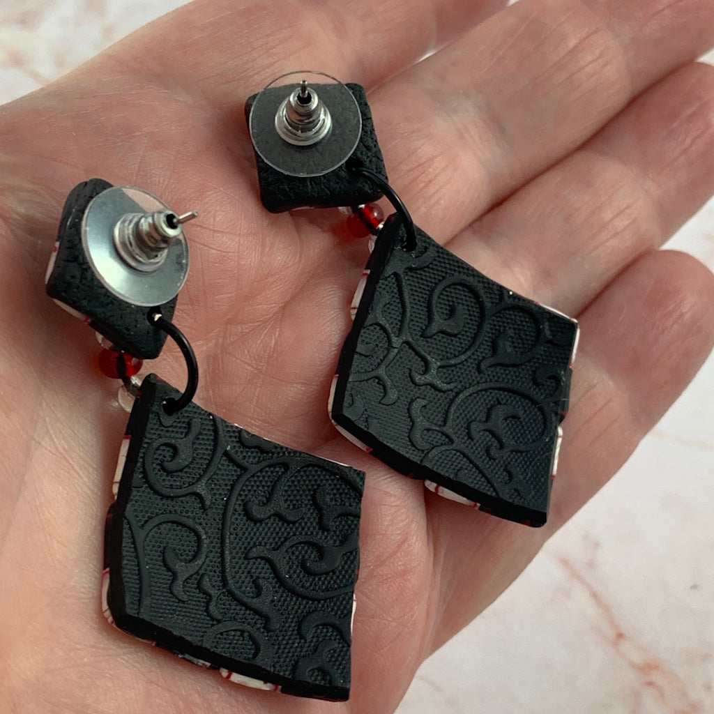 Back view of Australian artist made red diamond shape fashion earrings with embossed black textured finish and bead connector.