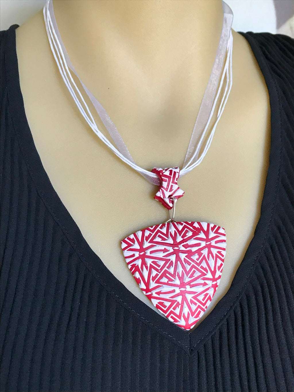 Front close-up of red and white textured pendant necklace worn on mannequin bust.