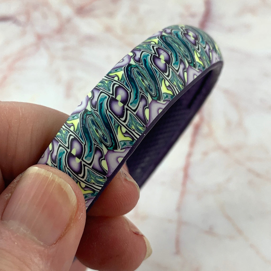 Top view of 20cm handmade polymer clay bangle by Rennique, statement bracelet with flowing multicolor pattern and smooth finish