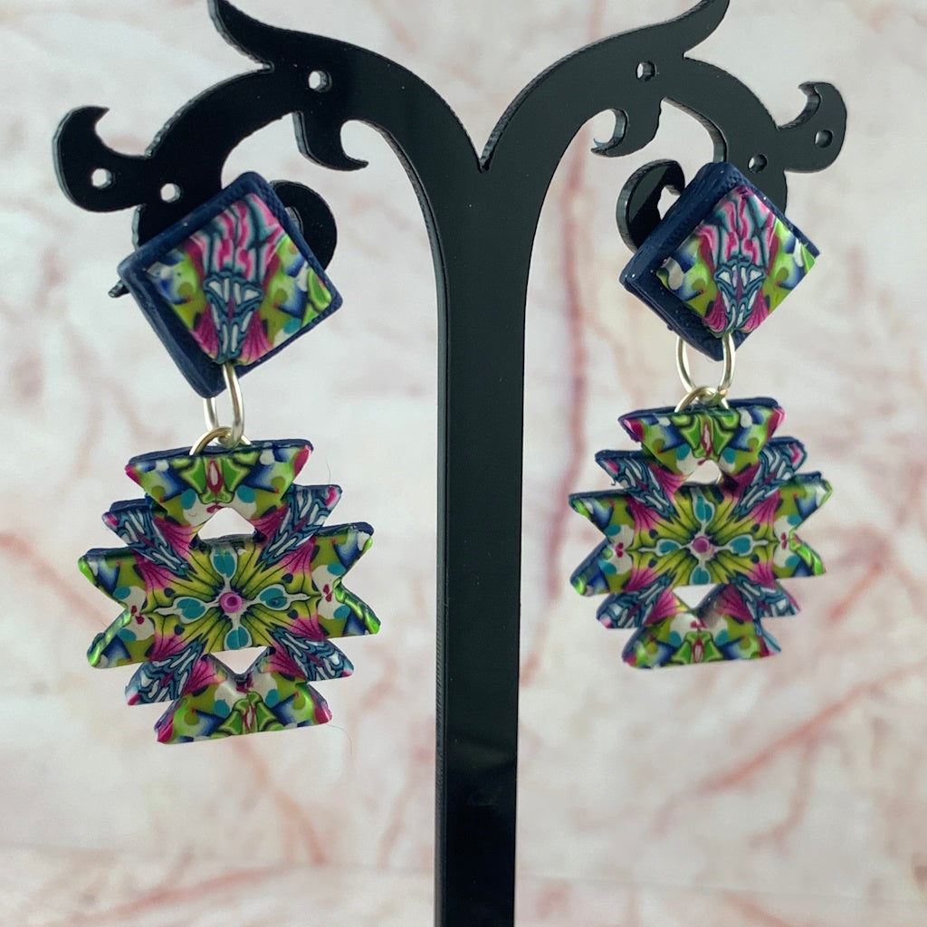 Australian handmade Aztec style fashion earrings hanging on display stand with vibrant multicolour geometric design.