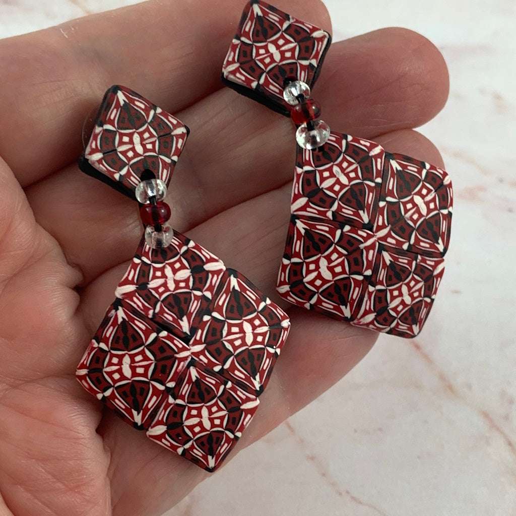 Close-up of handmade Australian red diamond fashion earrings with detailed geometric mosaic pattern and glass bead accent.