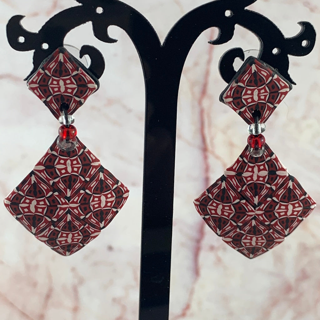 Front display of Australian artist made red diamond statement earrings with intricate red black and white geometric design.