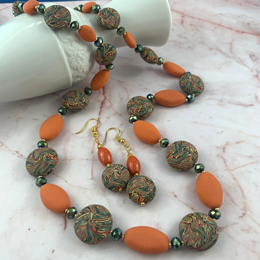 Long handmade necklace with autumn colour palette orange beads, green crystals and patterned beads