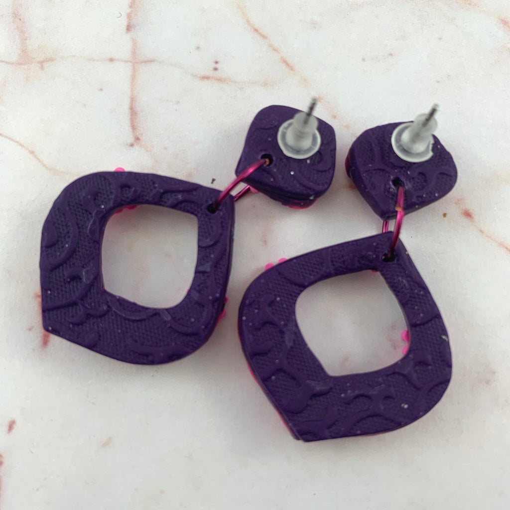 Back view of award-winning Rennique hand-sculpted red diamond shape earrings with textured purple finish and secure post fittings.