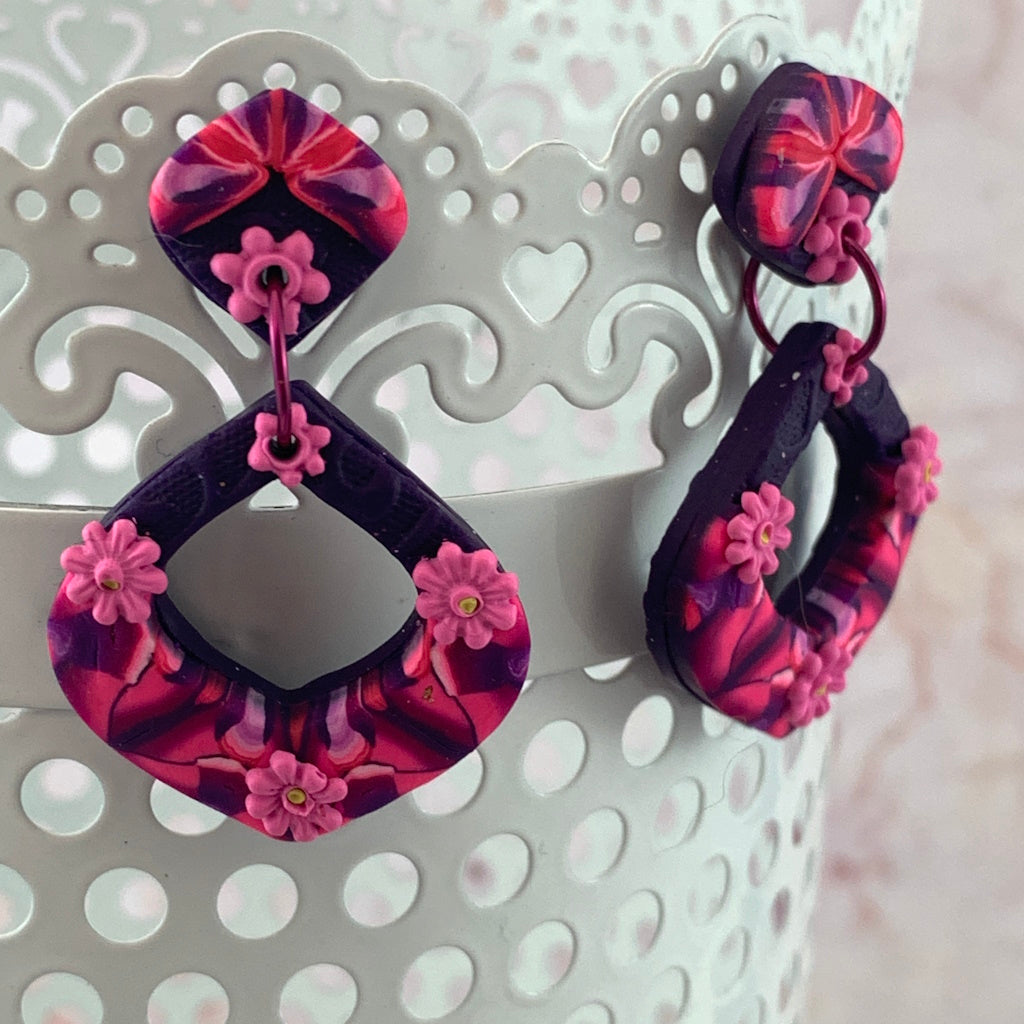 Award-winning Rennique hand-sculpted red diamond shape statement earrings in pink floral marbled design displayed as hero product image.