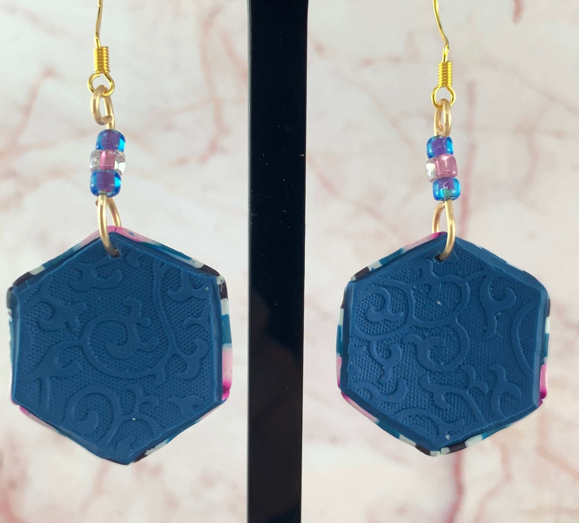 Back view of embossed polymer clay earrings with textured pattern and glass seed bead detail, contemporary jewellery