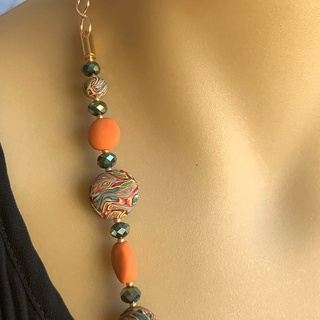Close up detail of orange oval beads and multicolour marble round beads on handmade long necklace