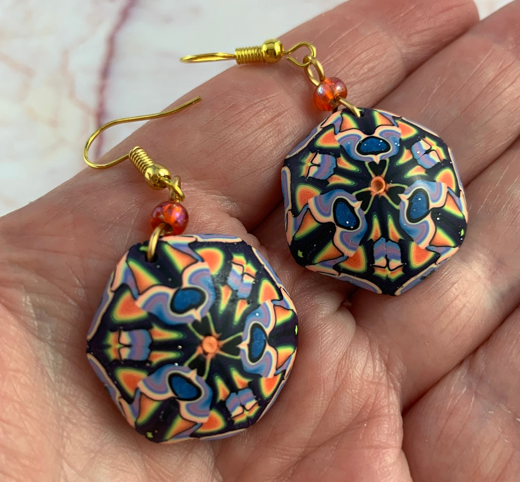 Close-up front view of colourful handmade earrings showing marbled bead pattern and artisan finish.