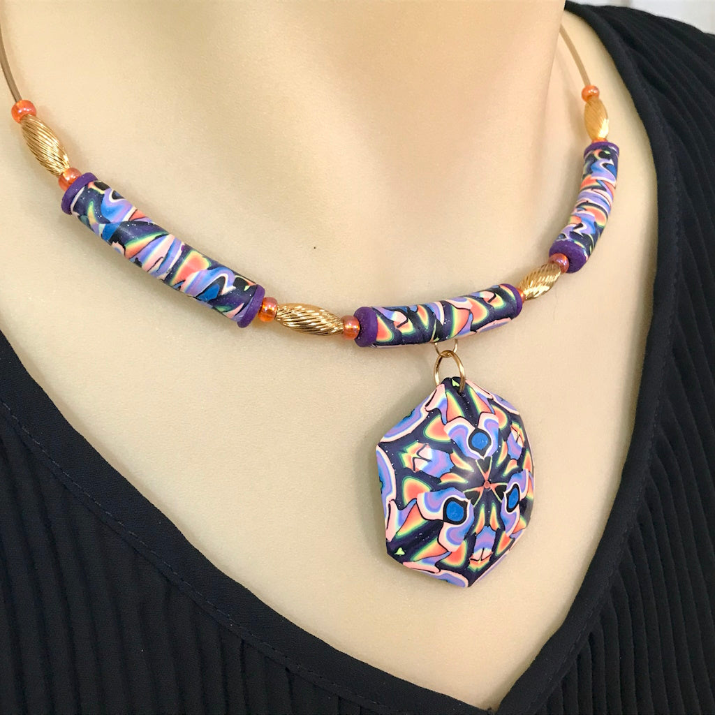 Handmade colourful geometric jewellery set worn, showing pendant and matching earrings.