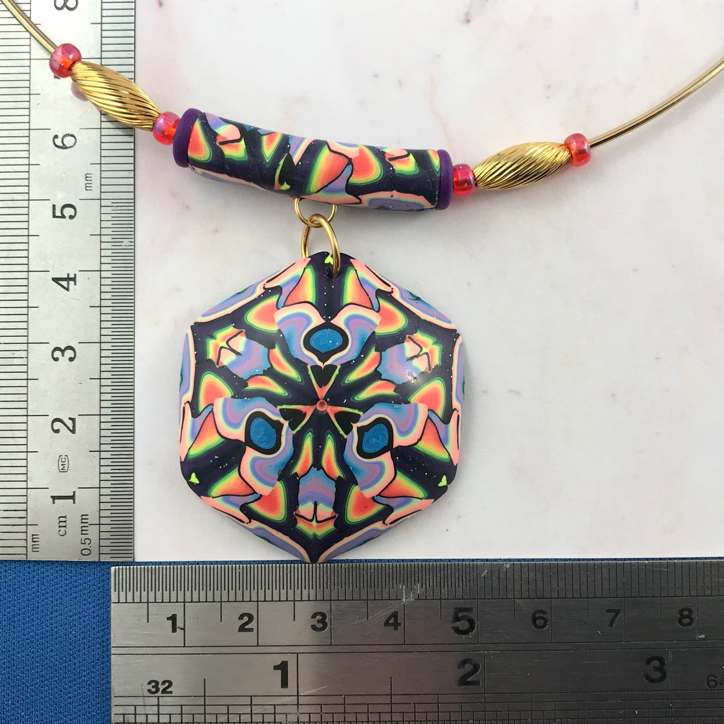 Close-up front view of colourful handmade necklace showing marbled bead detail and gold accent beads.