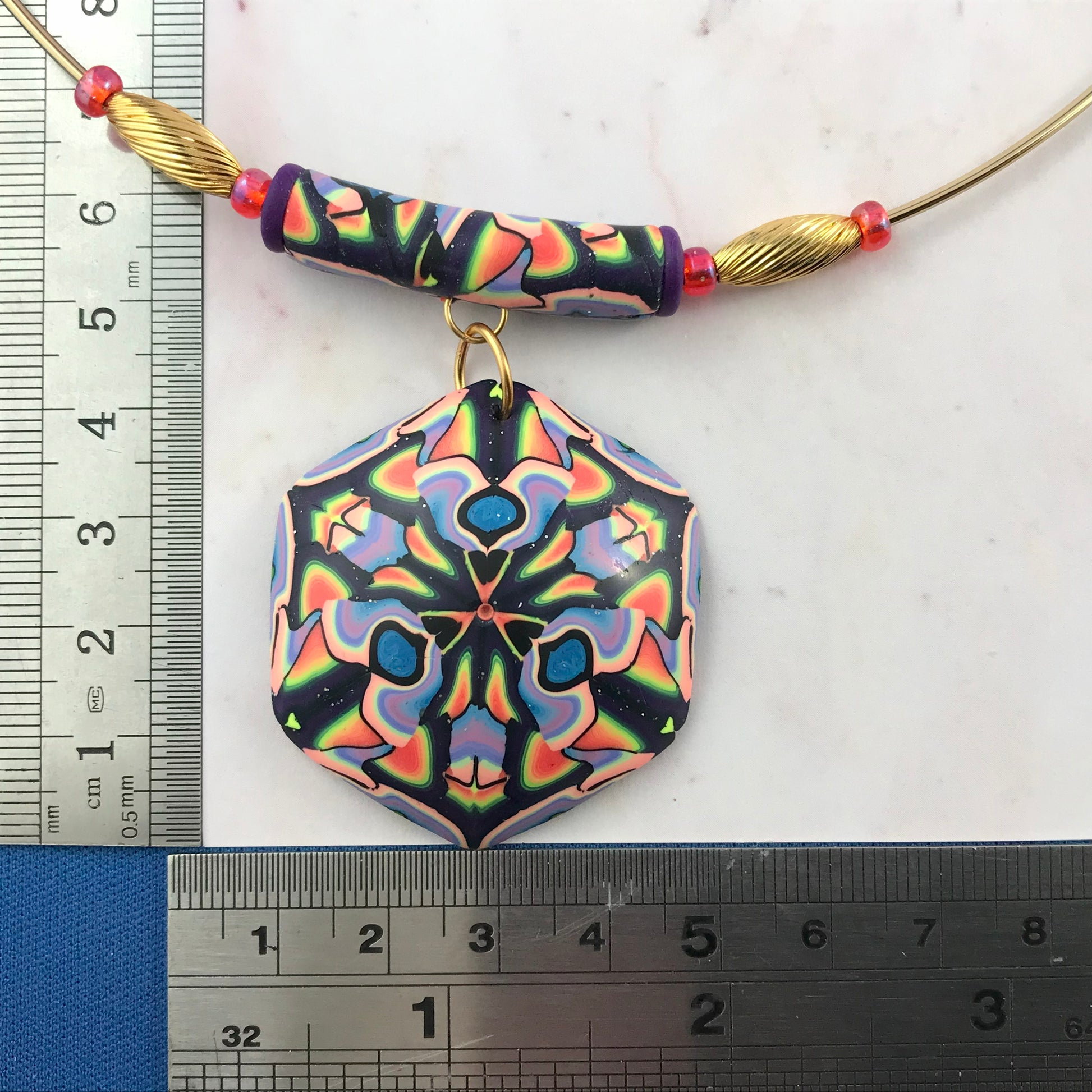 Close-up front view of colourful handmade necklace showing marbled bead detail and gold accent beads.