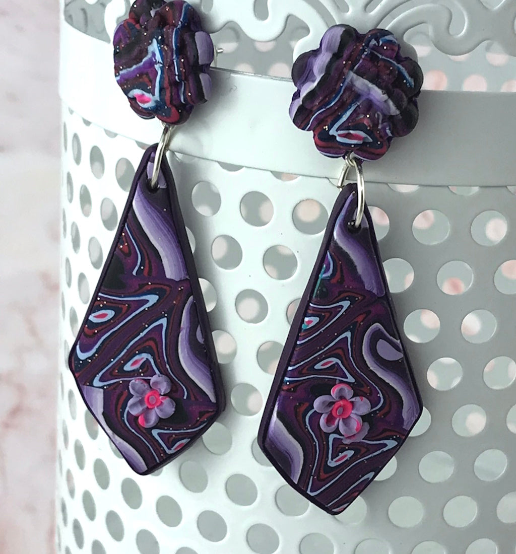 Rennique marbled purple polymer clay drop earrings displayed as bold designer fashion jewellery with floral detail.