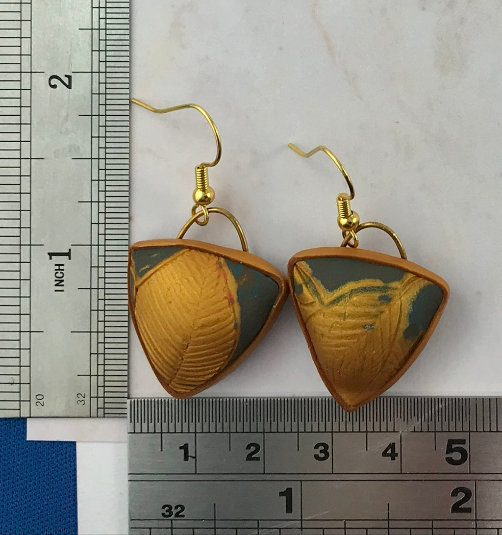 Handmade blue grey and gold triangle earrings with embossed leaf texture and gold hooks, shown with ruler for size reference.
