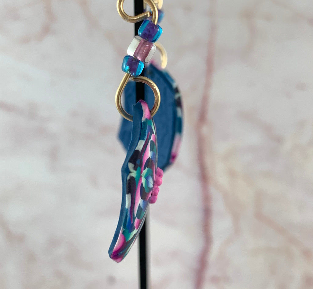 Side view of handmade floral earrings showing lightweight polymer clay design with gold hooks and glass beads