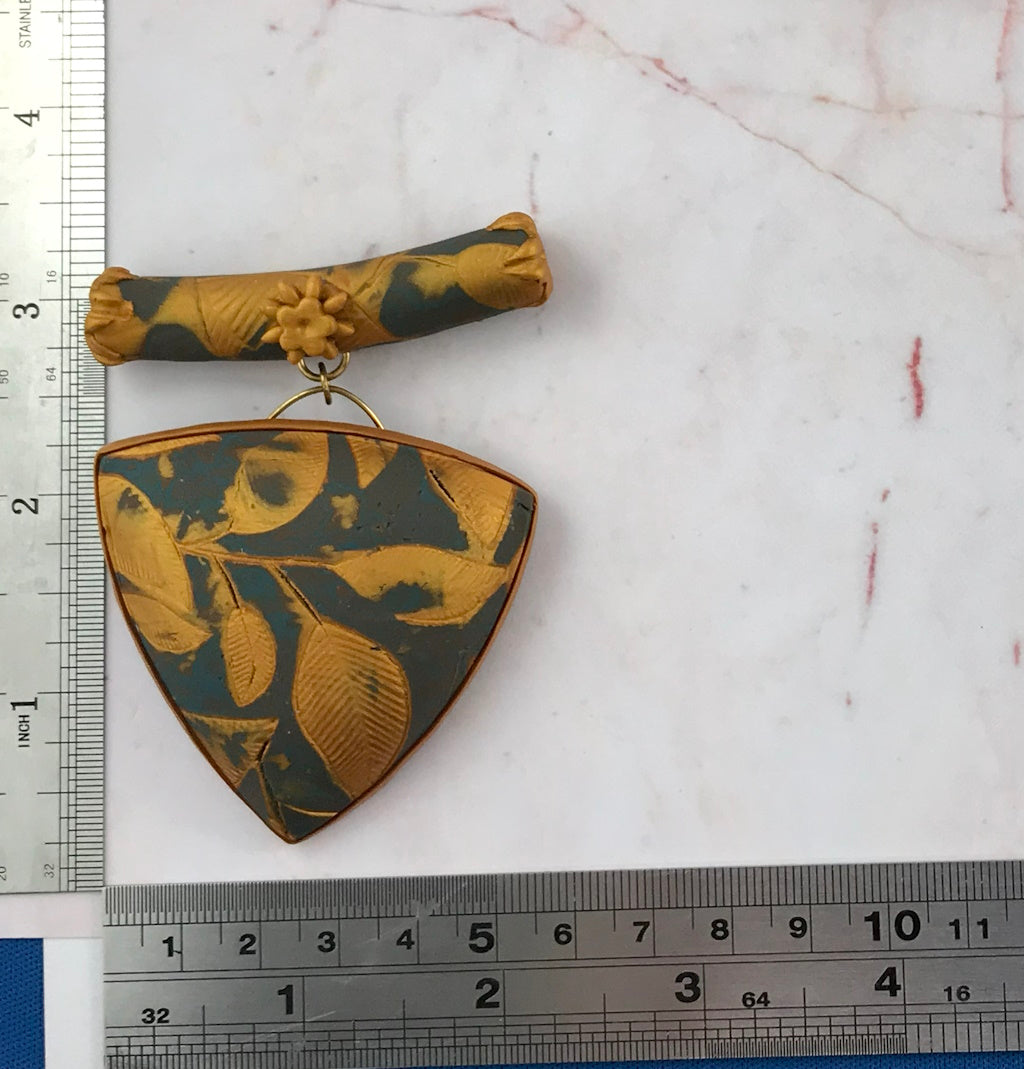 Handmade blue grey and gold polymer clay pendant necklace with embossed leaf design on gold neck ring, matching elegant jewellery set.
