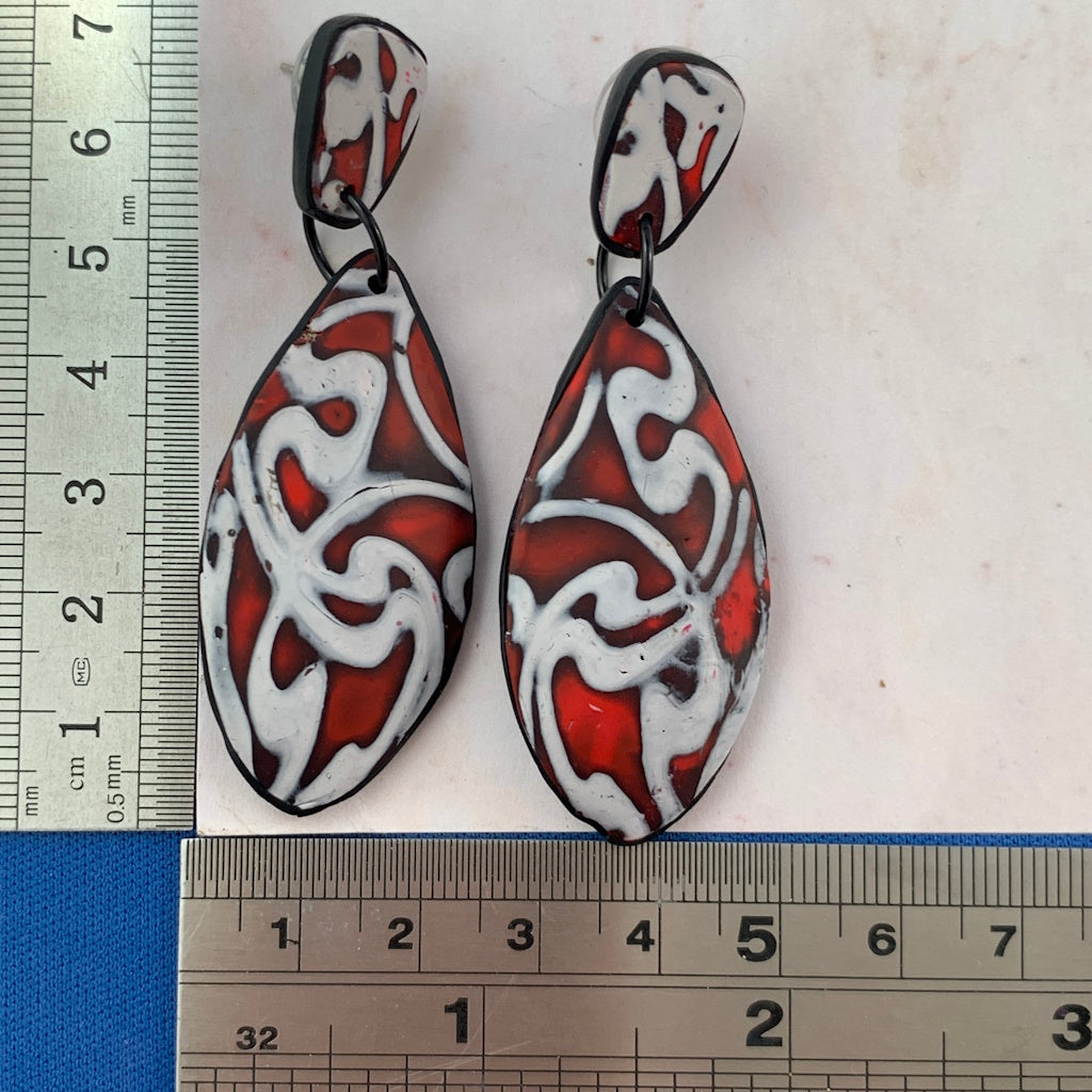 Handmade red statement earrings shown with ruler for size reference