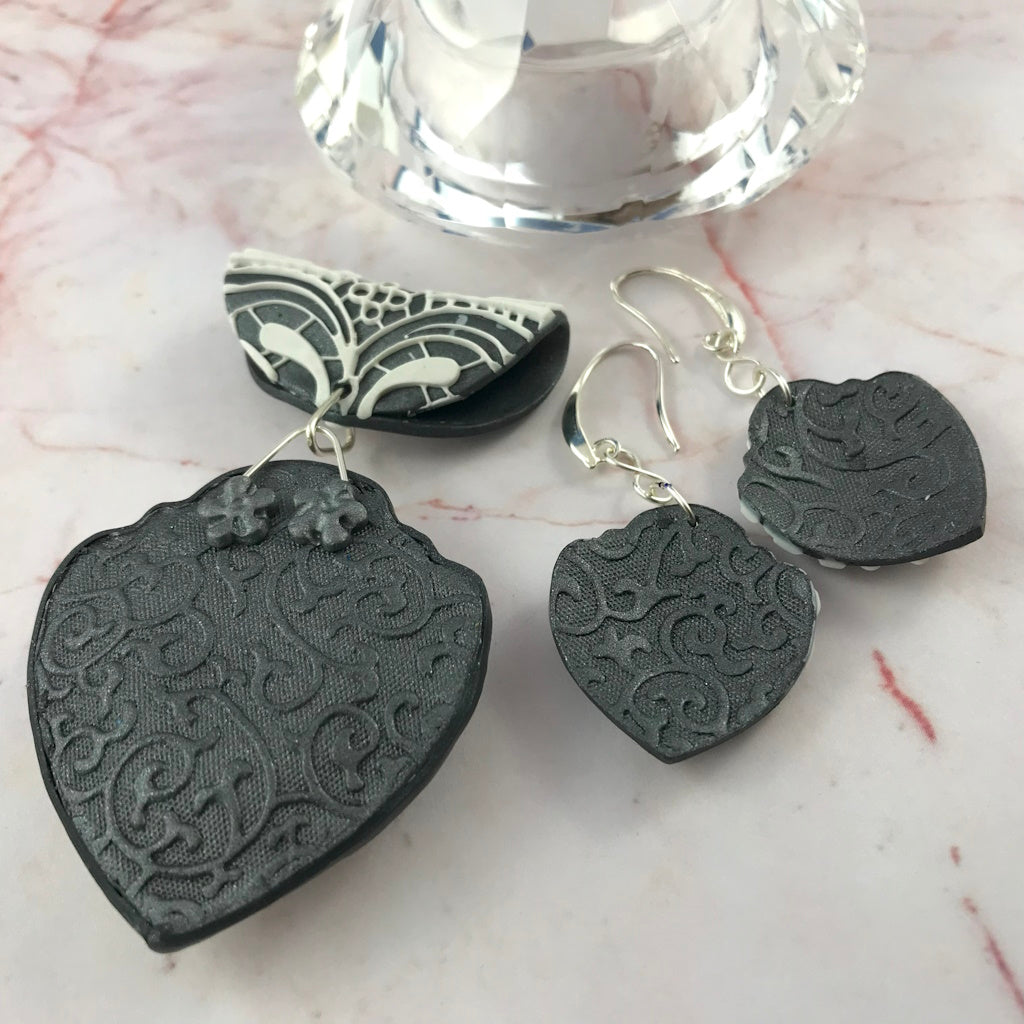 Back view of navy blue and white handmade jewellery set with patterned finish on pendant and earrings.