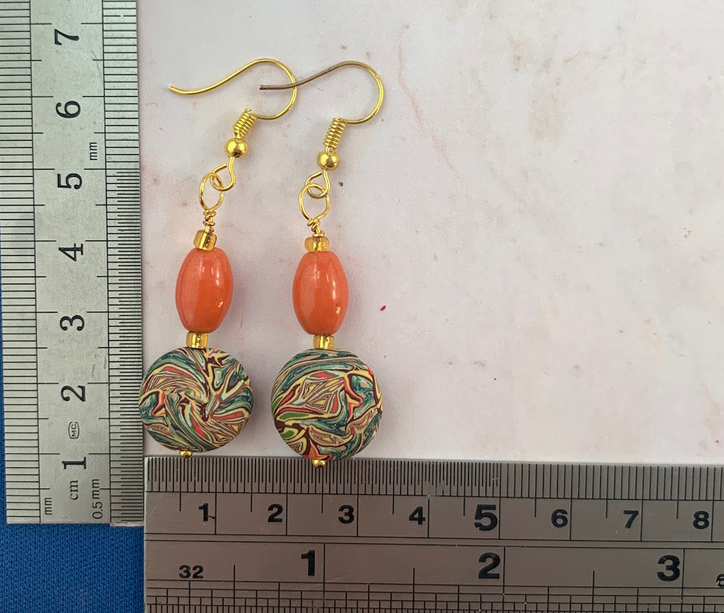 Close up of handmade orange and marble bead earrings with size reference ruler, gold hook artisan jewellery Australia