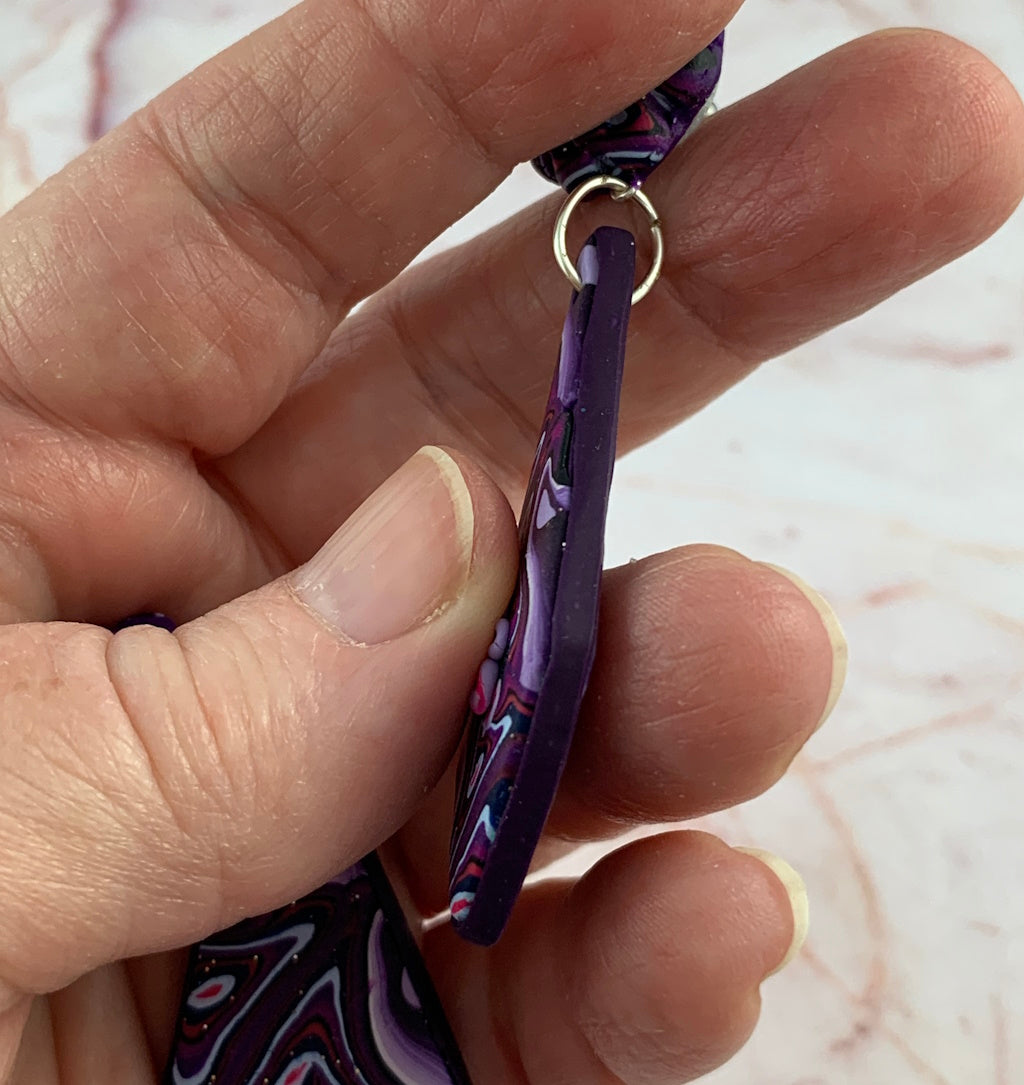 Side view of Rennique long purple polymer clay earrings showing slim statement drop shape and handcrafted finish.