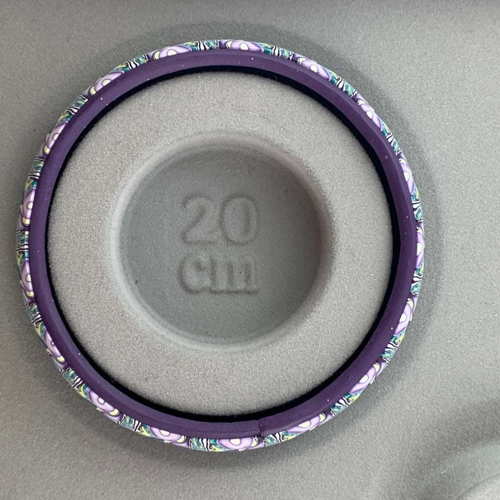 Detail view of Rennique polymer clay bangle showing layered flowing pattern in blue-green, lilac and pale yellow tones
