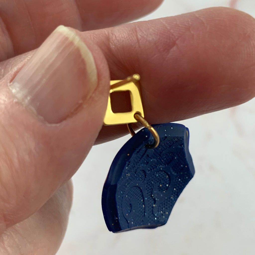 Back view of Rennique handmade blue statement earrings showing gold stud posts and textured finish.