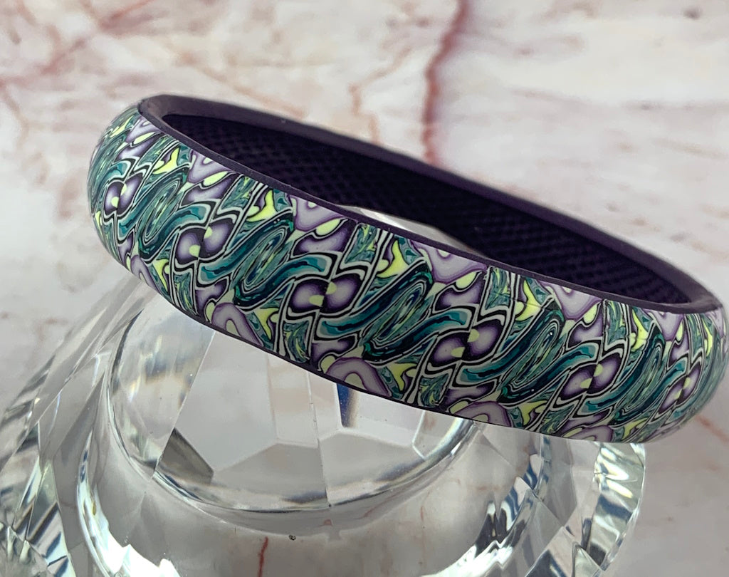 Rennique handmade polymer clay bangle close-up showing flowing blue-green, lilac and pale yellow pattern, artisan jewellery Australia