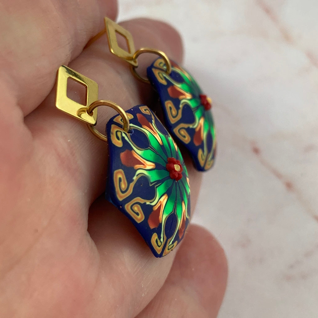 Side profile of handmade Rennique blue and green statement earrings showing curved artisan polymer clay surface.