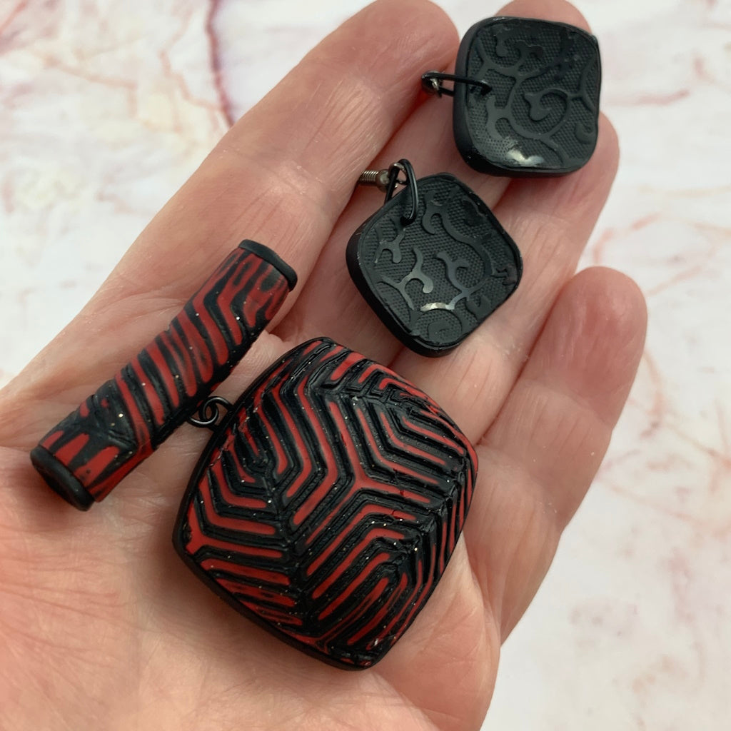 Rennique Australian artist made polymer clay pendant in high-contrast red and black geometric pattern detail