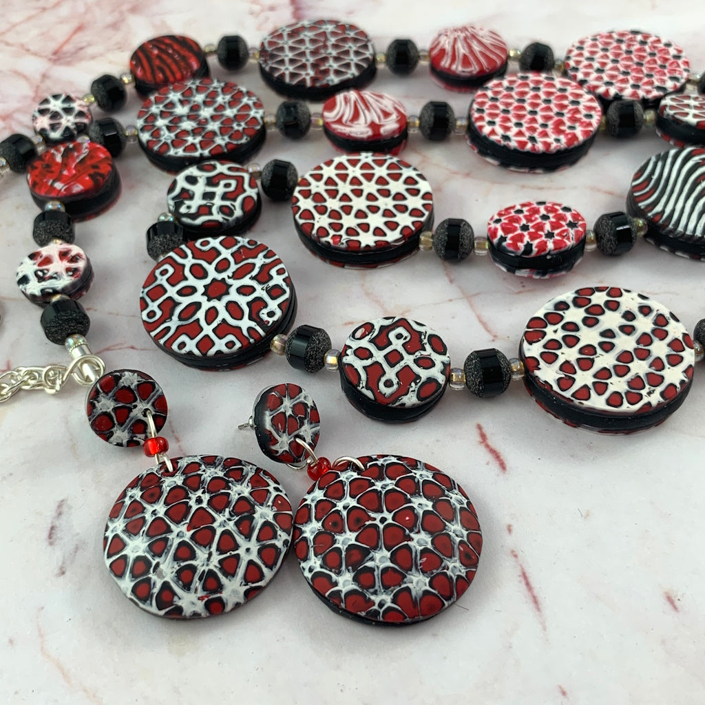 Rennique mokume ganae necklace and earring set close up red black white designer clay jewelry detailed patterned discs artisan statement wearable art