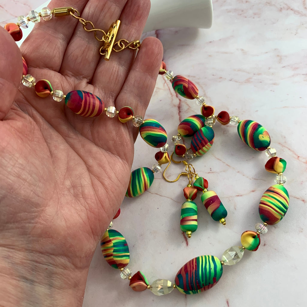 Close up of Rennique handmade multicolour statement necklace with vibrant striped polymer clay beads, crystal spacers and bold designer jewellery styling.