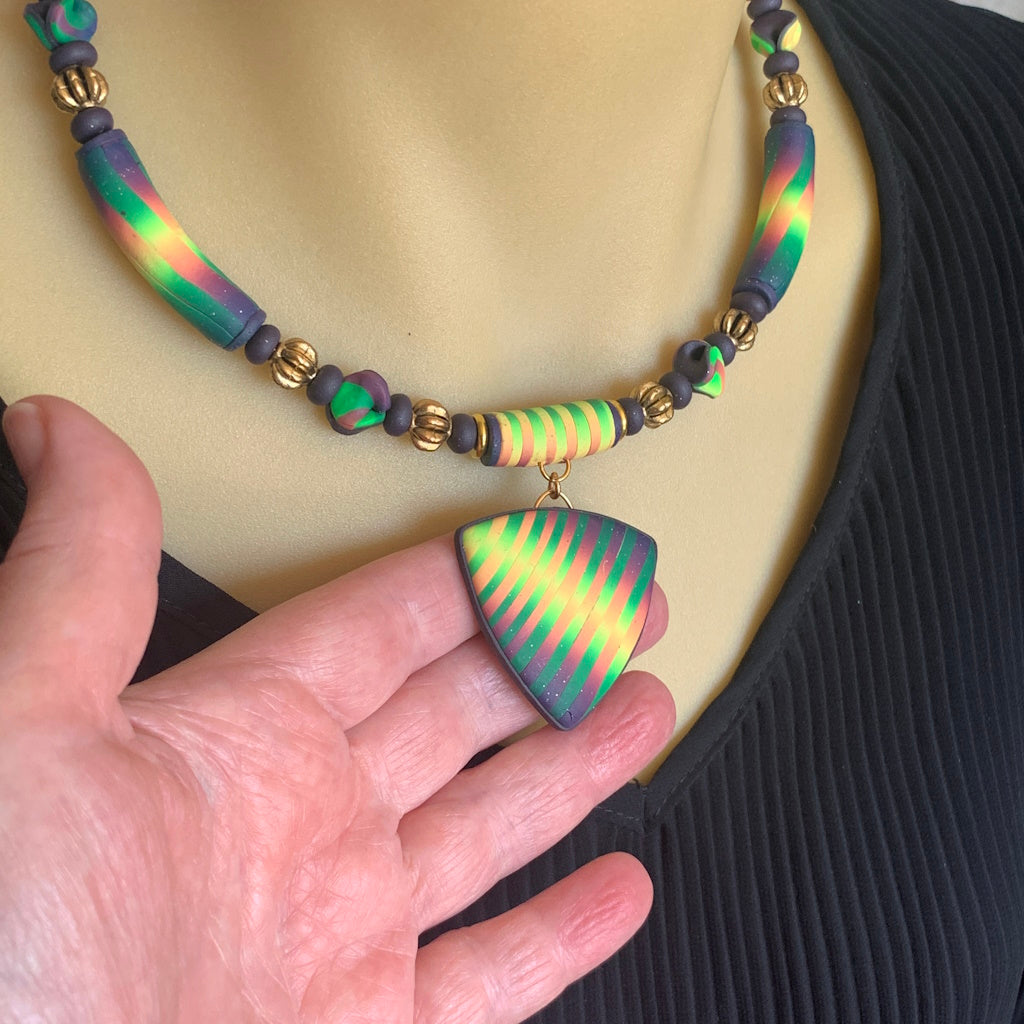 Award winning Rennique hand sculpted ladies short necklace featuring a multicolour striped statement pendant in green gold and purple artisan polymer clay design.