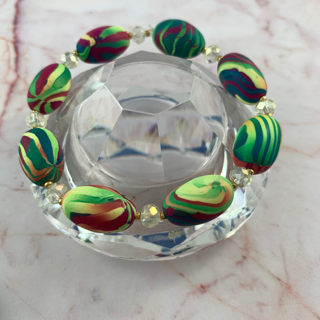 Close up of Rennique handmade multicolour stretch bracelet featuring vibrant striped artisan beads in teal, pink, yellow and green with crystal accents and gold spacer details.