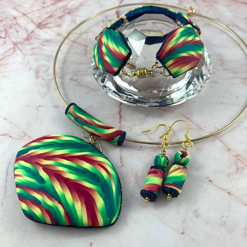 Rennique handcrafted multicolour statement jewellery set featuring bold pendant necklace, matching drop earrings and coordinating bracelet in vibrant green, pink and teal artisan polymer clay design.