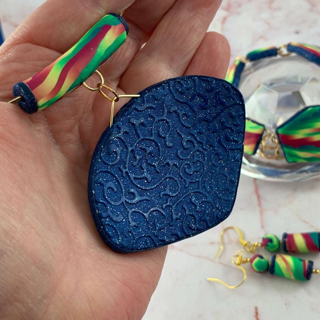 Back detail of Rennique handmade statement pendant featuring textured navy blue embossed finish with gold collar wire and matching artisan jewellery set.