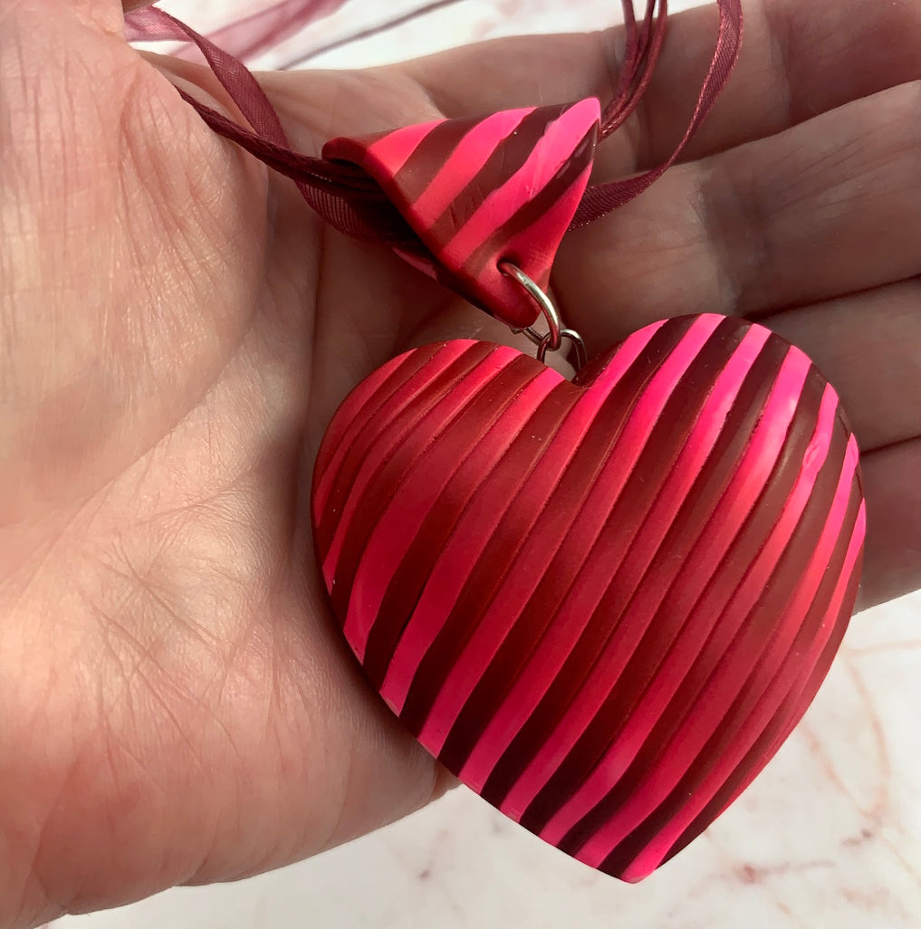 Statement heart jewellery set featuring a large red and pink striped pendant necklace.