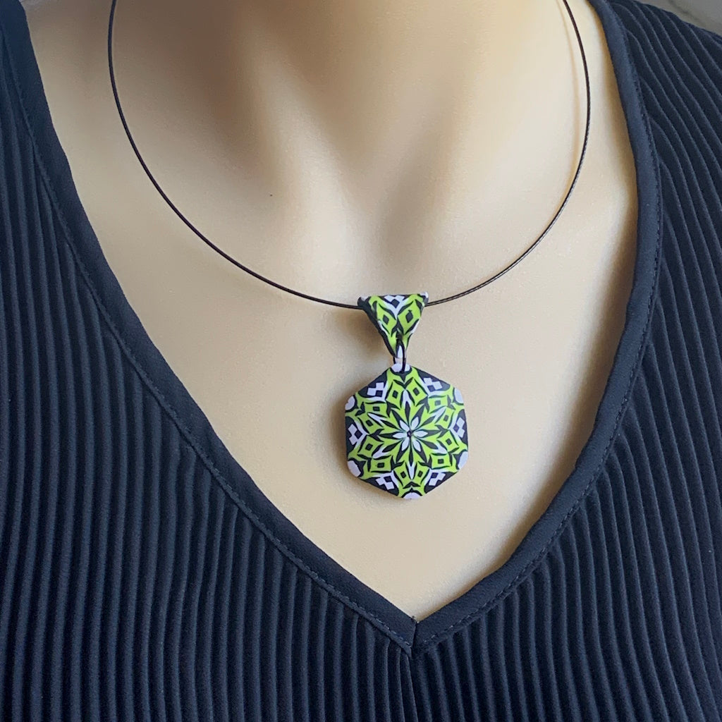 Rennique lime green geometric mandala pendant necklace displayed on mannequin for styling and size reference.
