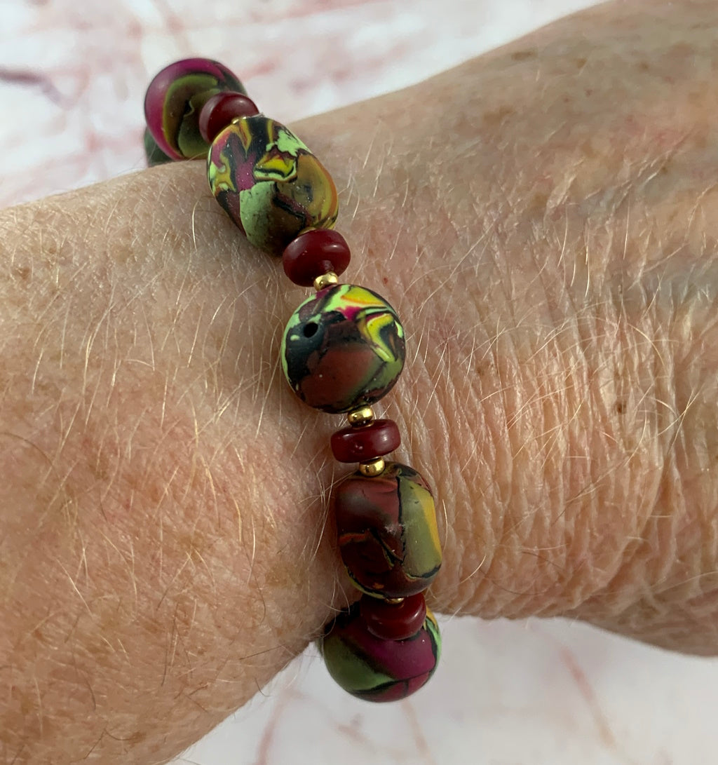 One-of-a-kind contemporary polymer clay bracelet worn on wrist, featuring handcrafted patterned beads in summer colours.
