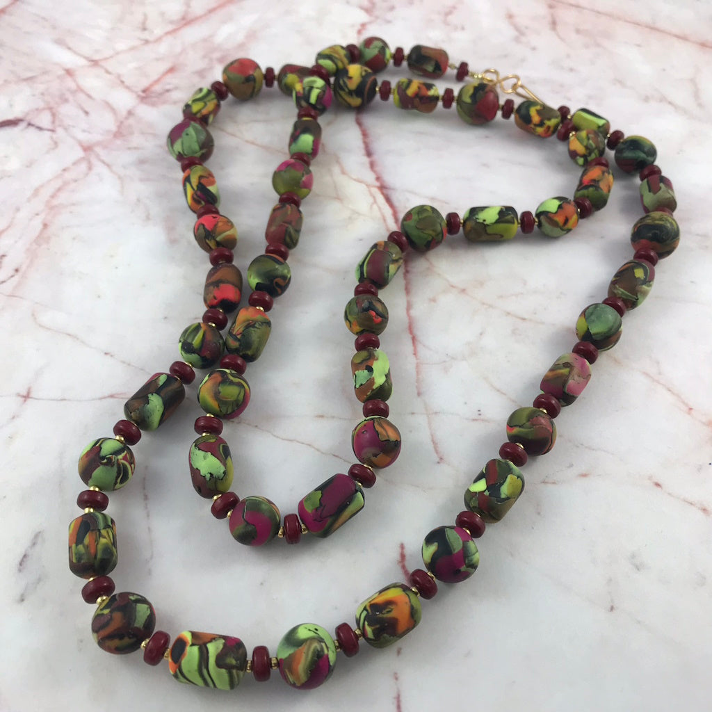 Close-up of handcrafted polymer clay beads showing textured selective collage pattern detail.