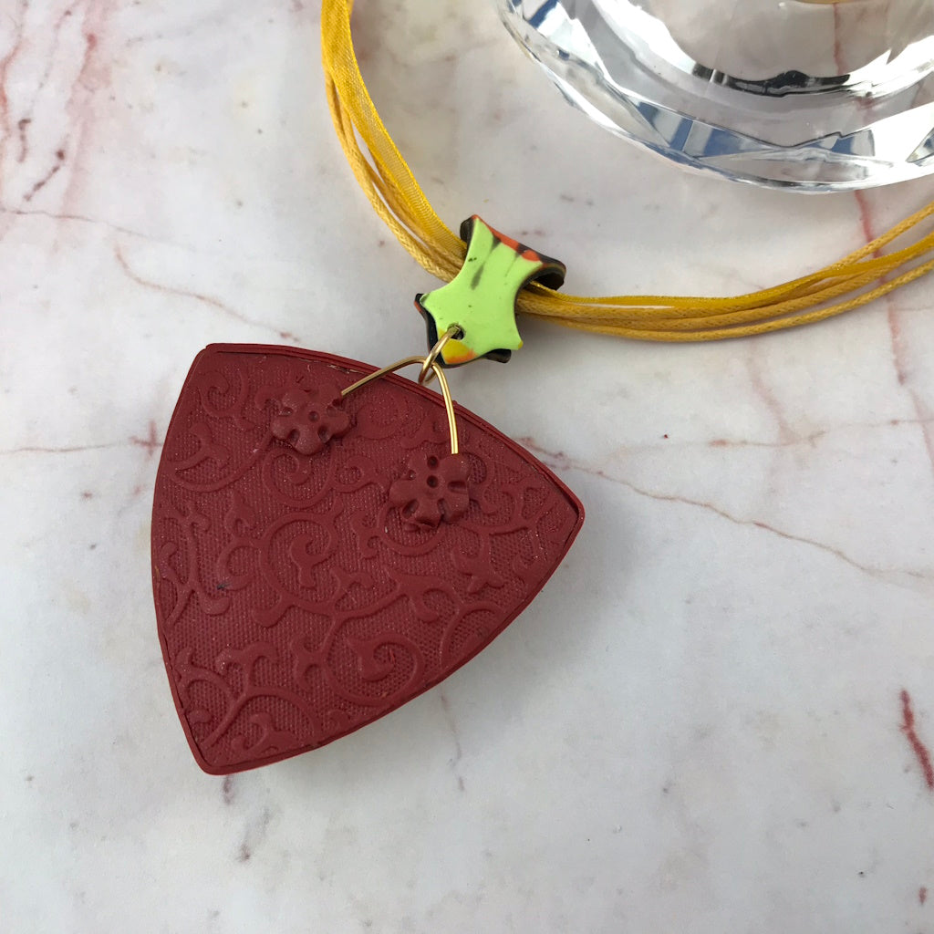 Back view of handmade pendant necklace with patterned artisan finish.