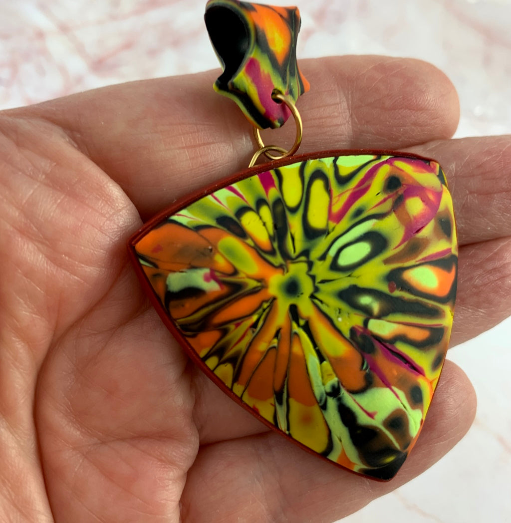 Close-up of textured summer pendant necklace showing layered polymer clay pattern detail.