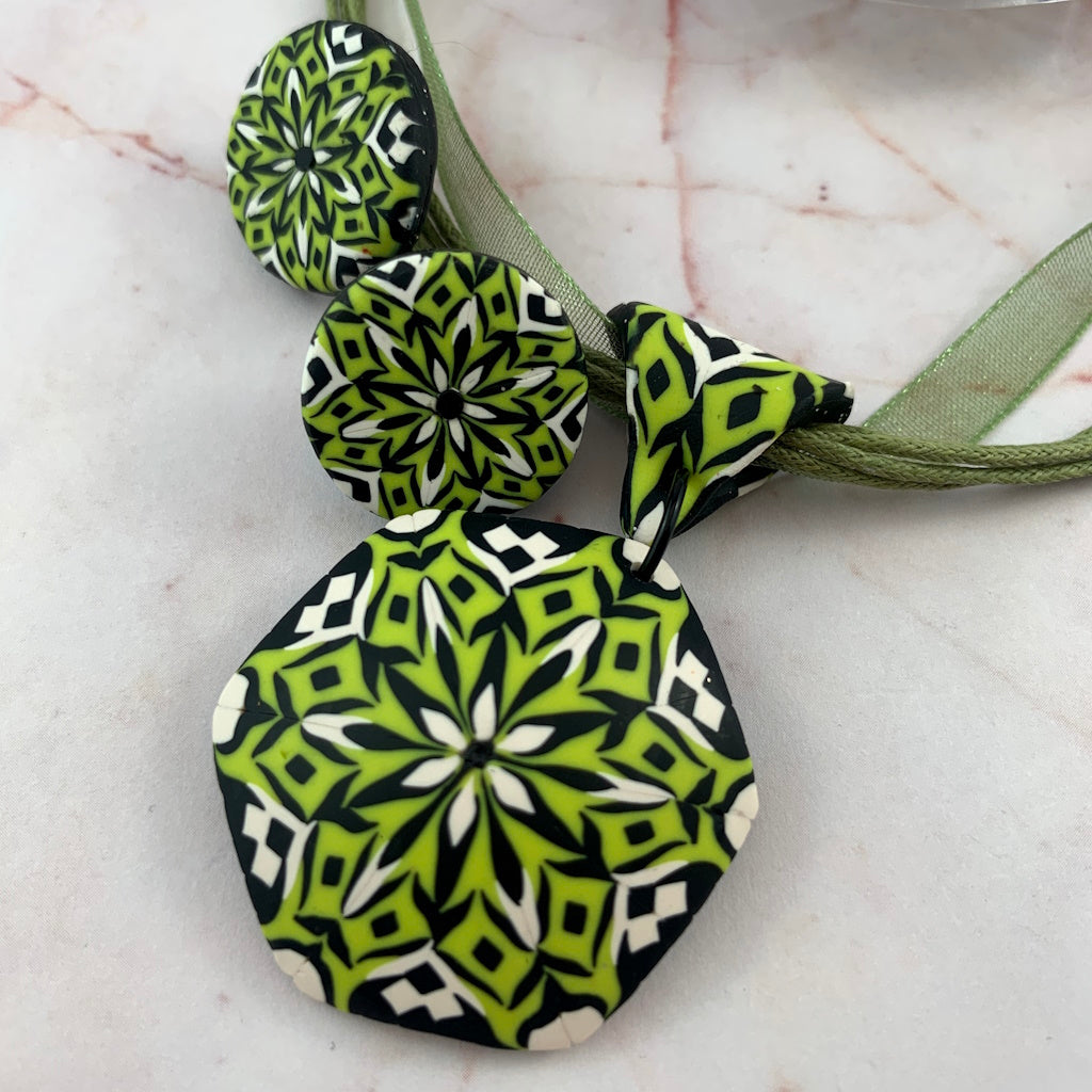 Rennique handcrafted lime green, black and white polymer clay pendant necklace with matching round stud earrings in bold geometric pattern.