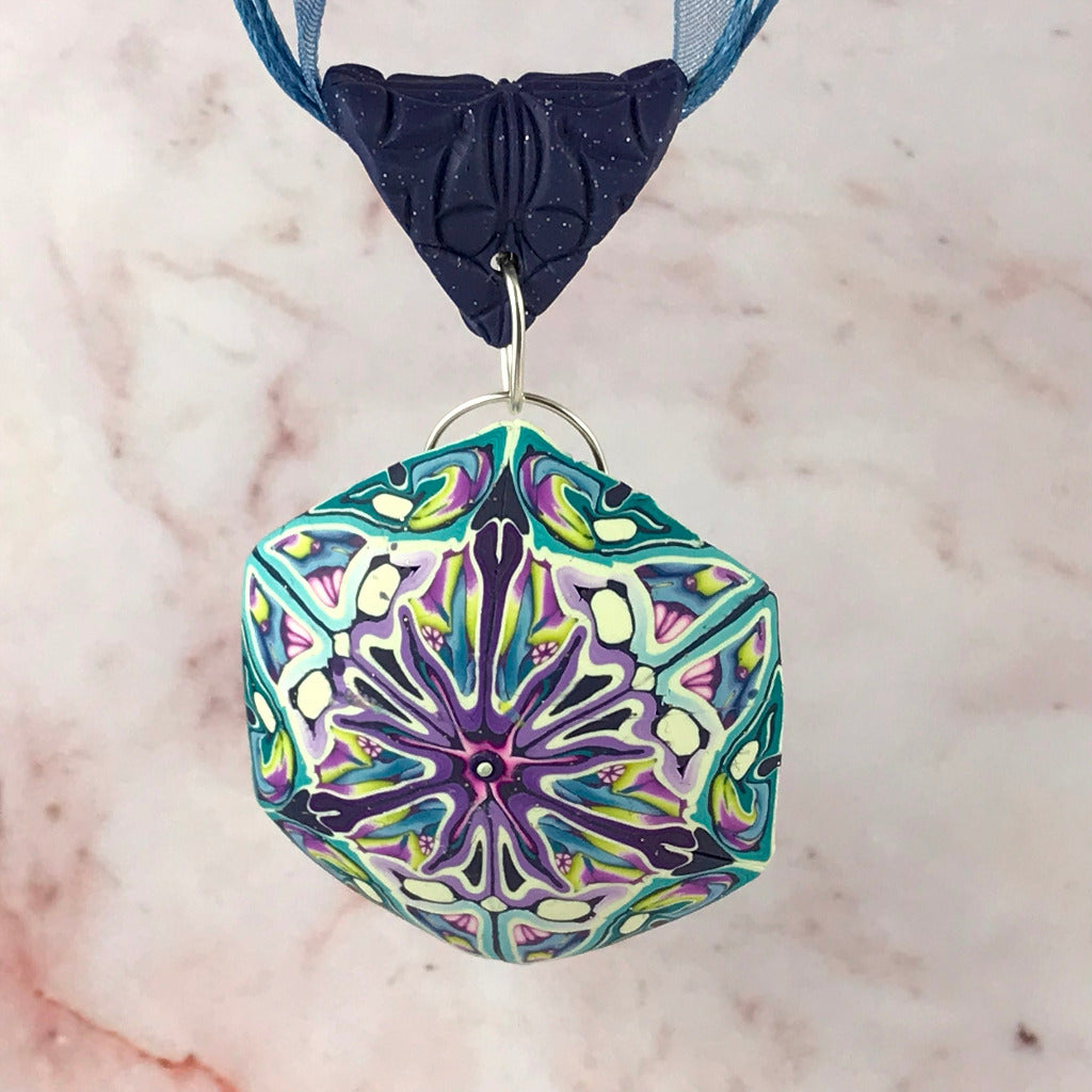 Close-up hanging display of abstract floral polymer clay pendant necklace inspired by passionfruit flower petals