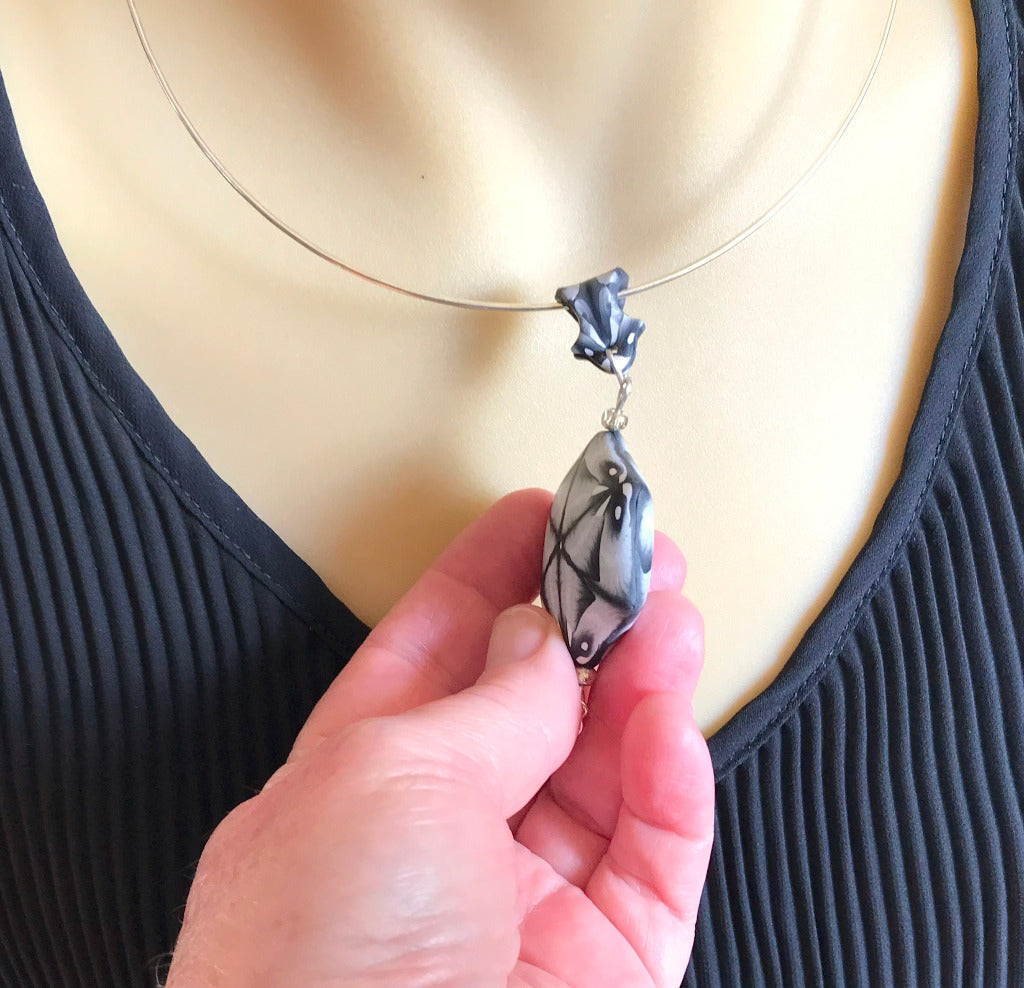 Handmade black white polymer clay pendant necklace worn on silver neck ring, elegant monochrome statement jewellery handmade in Australia