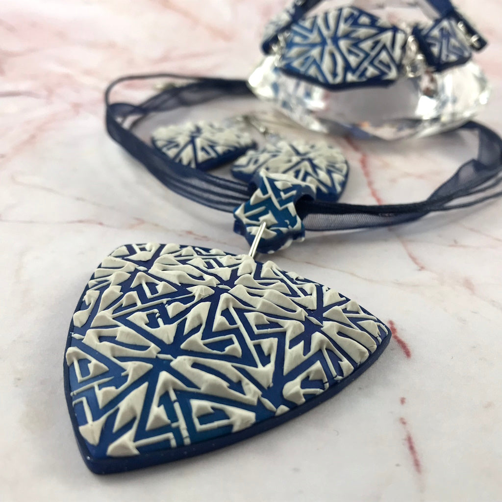 Front view of handmade blue and white geometric polymer clay bracelet with silver link connectors.