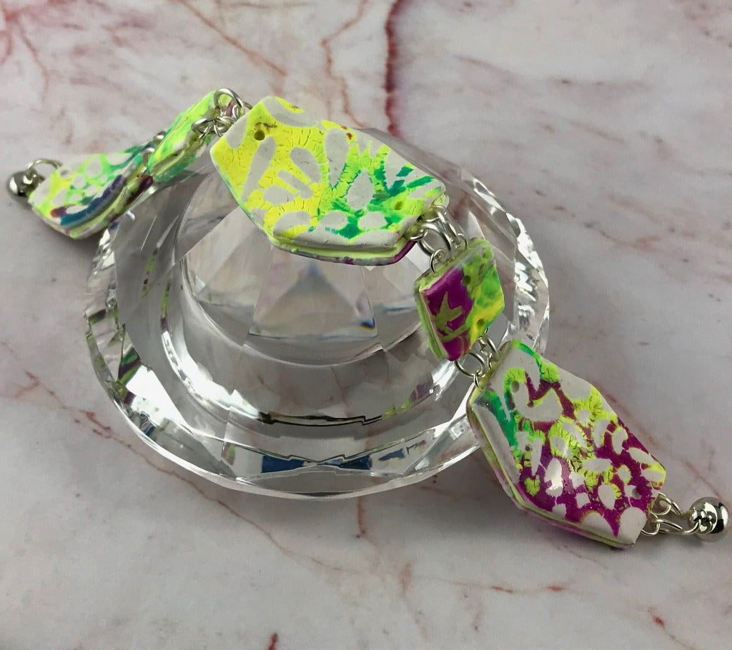 Back view of handmade bold abstract bracelet displayed on glass showing patterned reverse side.