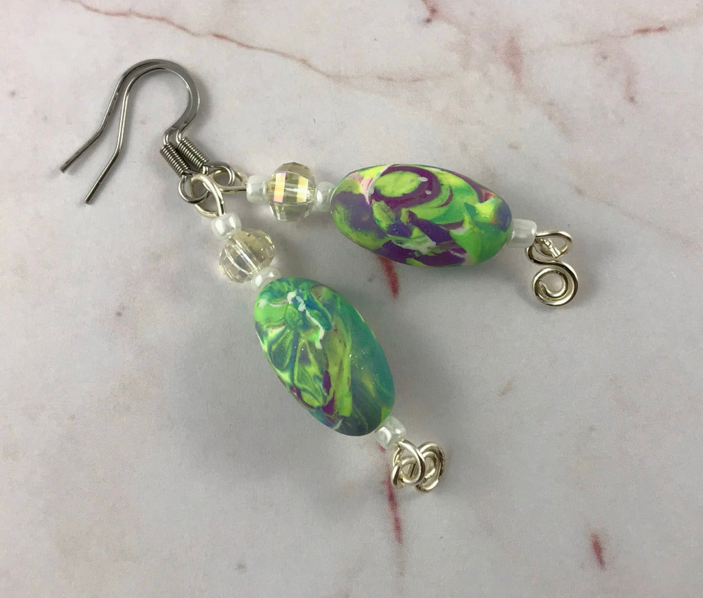 Close-up of handmade bold abstract polymer clay earrings with matching curved design.