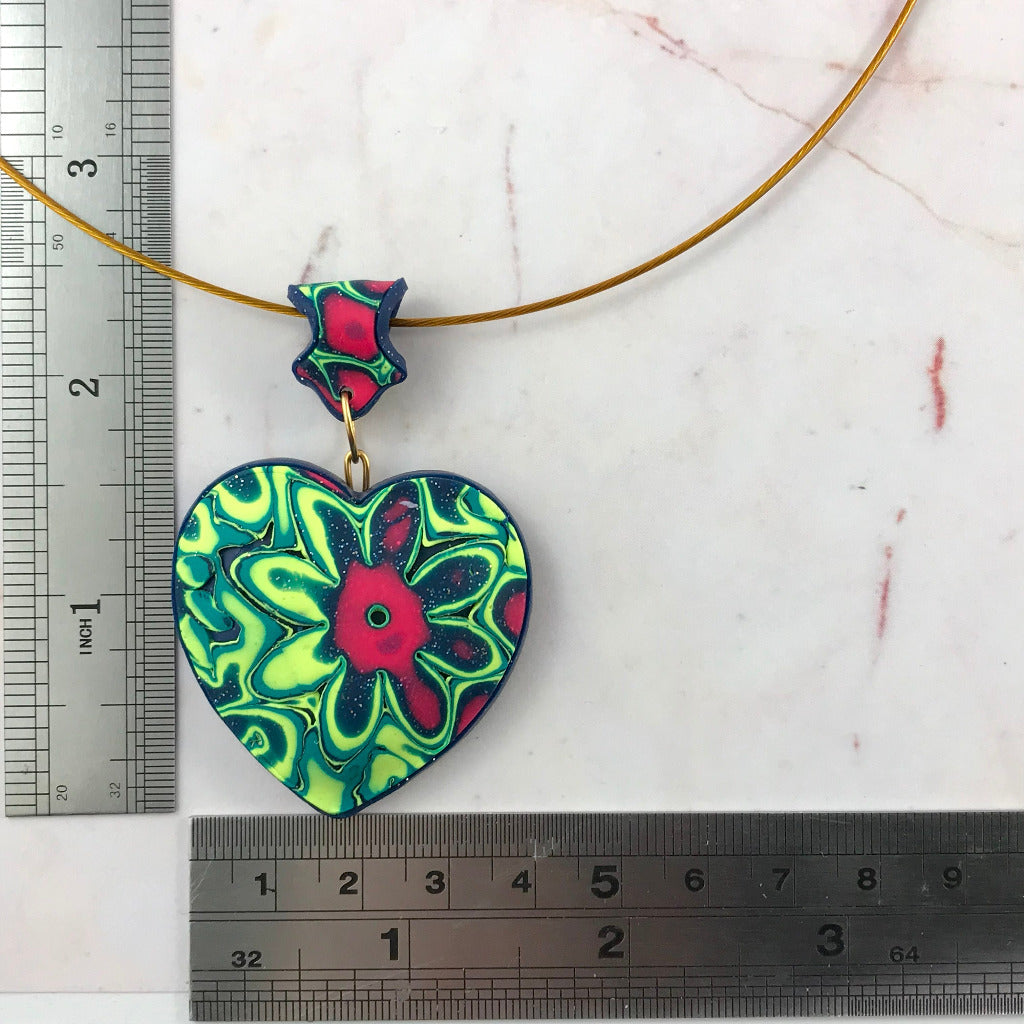 Close-up handmade heart pendant necklace in neon green, navy and pink polymer clay floral design, statement jewellery Australia