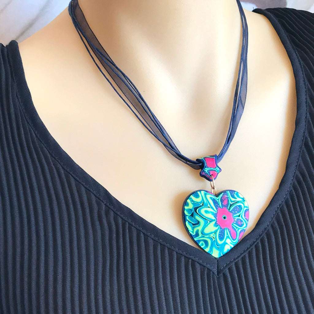Handmade heart pendant necklace worn on model featuring bold neon green floral polymer clay design, Australian artisan jewellery