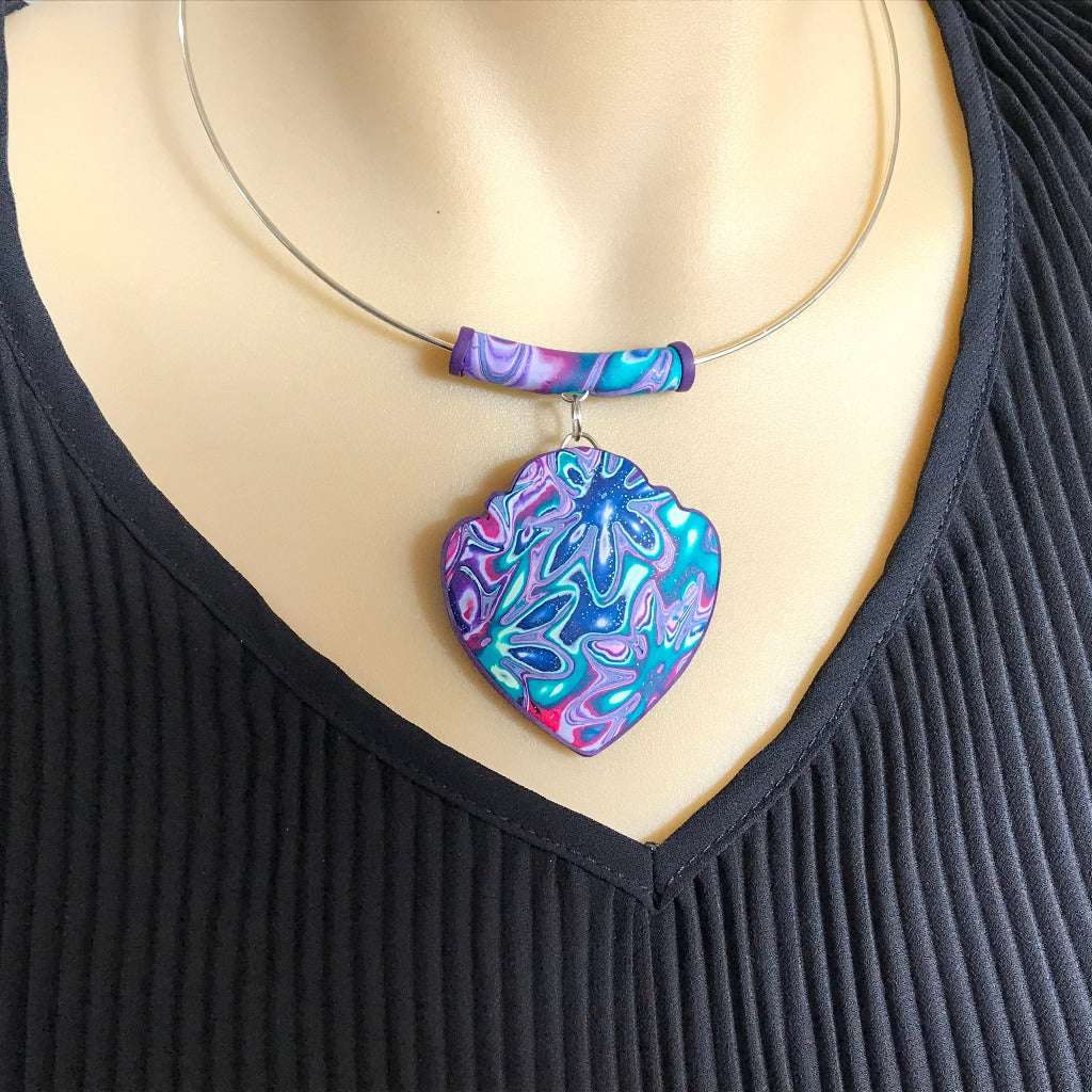 Close-up handmade heart pendant necklace in purple, teal and pink marbled polymer clay with cosmic floral pattern, statement jewellery Australia