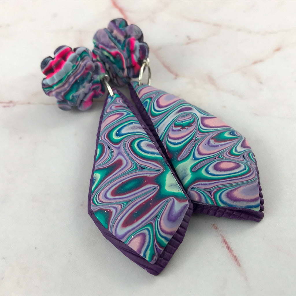 Close-up of handmade purple and teal marbled polymer clay dangle earrings with artisan floral swirl pattern, unique Australian jewellery